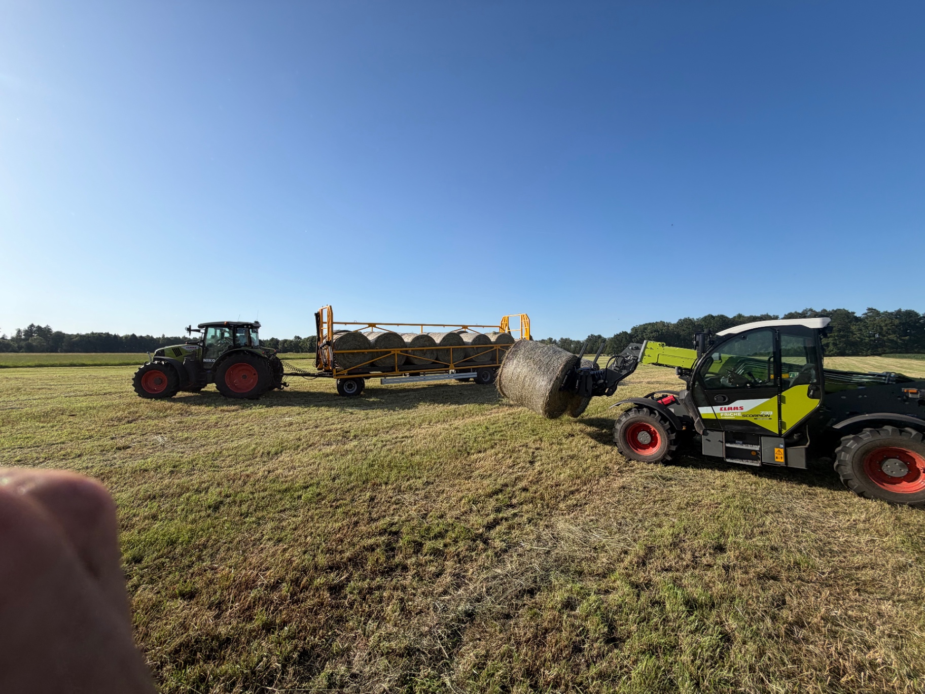 Traktor mit Ballenanhänger auf dem Feld